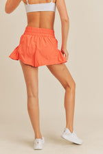 SMOCKED FLIRTY ACTIVE SHORTS IN CORAL